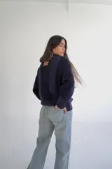 Sweater de punto azul marino con cuello redondo y mangas largas. Presenta textura trenzada en los laterales y detalle de estrellas bordadas en blanco en el centro, con la inscripción "Del Sur" en la parte superior.