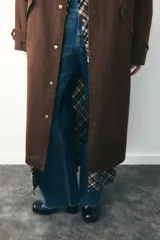 Trench color verde oscuro con cuello solapa combinado en pana marrón y manga larga. Detalle de acabados con trabillas y pinza en espalda. Bolsillos delanteros con solapa y botón a presión. Tejido encerado efecto lavado. Cierre frontal con botones a presión.