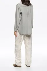 Pantalón tobillero de corte barrel, tiro medio, confeccionado en mezcla de algodón. Presenta un estampado de piel de serpiente en tonos beige y blanco, cierre frontal con botón y cremallera, diseño de cinco bolsillos y costuras irregulares.