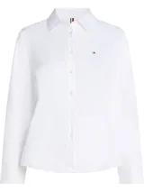 Camisa blanca de popelín de mezcla de algodón elástico, corte regular, cuello inglés, puños con botón y logo de Tommy Hilfiger bordado en el pecho.