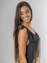 Vestido midi negro con estampado tropical de hojas y flores en tonos tierra, naranja y verde. Es de tirantes anchos con nudo regulable en el hombro y tiene aberturas laterales.