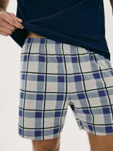 Conjunto de pijama para hombre compuesto por una remera azul marino de manga corta con cuello en V y un short a cuadros en tonos azul, gris y blanco.
