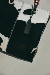 Cartera tipo tote de cuero nonato con diseño de manchas blancas y negras.