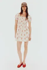 Vestido corto de popelina de algodón color blanco con estampado floral en tonos rosados. Tiene escote cuadrado con elástico, mangas cortas abullonadas con elástico y cuerpo fruncido.
