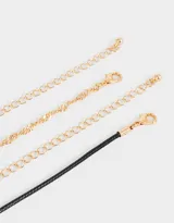 Set de dos chokers: uno de cadena dorada y otro de cordón negro con dije esmaltado de vaquita de San Antonio.