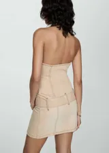 Minivestido de jean color beige, con cuello halter, cierre frontal con cremallera y cinturón con hebilla.