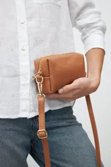 Bandolera rectangular color marrón, con correa larga ajustable y cierre superior con cremallera dorada.