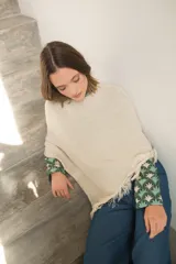 Poncho tejido en hilo de algodón color crudo con lurex y flecos en el ruedo.