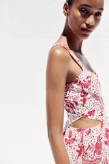 Vestido midi con estampado floral en tonos rosados, de escote recto y tirantes anchos con abalorios. Presenta aberturas laterales en la cintura y cierre trasero con cremallera oculta.