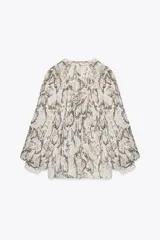 Camisa semitransparente con estampado animal print en tonos beige y marrón, de cuello redondo y escote pico, con mangas largas abullonadas. Detalle de volantes e hilo metalizado. Cierre frontal con botones.