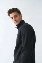 Buzo negro de tejido bondeado con medio cierre y logo en goma.