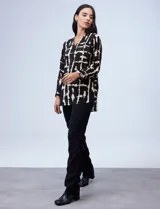 Blusa negra estampada con cuello a la base, escote en V y abertura con botones. Mangas 3/4 regulables con presilla y botón.