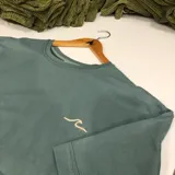 Remera verde agua de corte oversized, confeccionada en jersey 100% algodón. Presenta un pequeño logo estampado en el pecho.