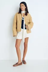 Campera color beige de algodón Oxford con cuello de pana marrón en contraste. Modelo de corte holgado con cierre frontal, hombros caídos, bolsillos laterales ribeteados y bolsillo superior con cierre. Ajuste con botones a presión en los puños y en la parte posterior del bajo.
