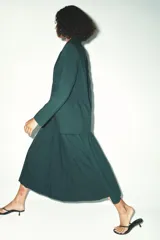 Falda midi verde oscuro con tablas, de tiro alto y cierre trasero con cremallera oculta.