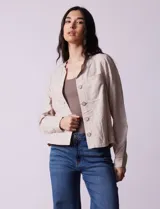 Chaqueta color beige de lino y rayón, con cuello mao, cierre frontal con botones y bolsillos delanteros.