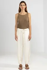 Pantalón de trabajo color crema, de corte relajado, confeccionado en lino y tencel. Con bolsillos laterales, cintura elástica, cordón ajustable y detalle regulable en el tobillo.