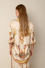 Blusa color crema con estampado floral y detalles de diseño barroco, con cuello mao, mangas 3/4 y cierre frontal con botones.