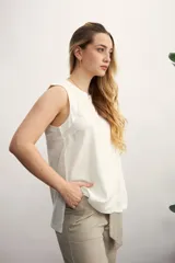 Blusa color crema sin mangas, de lino, con cuello redondo y corte recto.