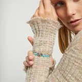 Pulsera de hilo elástico doble color turquesa, con dije central de corazón plateado de forma irregular y un cierre de bola metálico plateado.