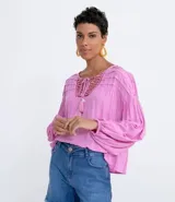 Blusa tipo blusón color rosado, de viscosa, con cuello redondo, manga larga acampanada, pliegues en los hombros, detalle de entredós en el escote y tiras de ajuste con borla.