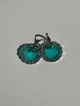 Aros colgantes con dije circular de resina color turquesa, bordeado con strass plateado y arito de acero quirúrgico.