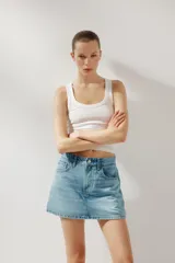 Minifalda de jean celeste con tiro medio, trabillas, cinco bolsillos y cierre frontal con cremallera y botón metálico.