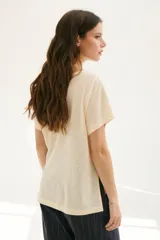 Blusa color crema con estampado de lunares negros, cuello redondo y mangas cortas.