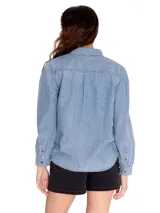 Camisa de manga larga celeste de denim con dos bolsillos en el pecho y cierre con botones metálicos.