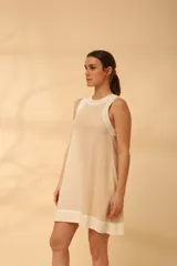 Vestido corto color beige claro, sin mangas y de corte recto. Confeccionado en lino.