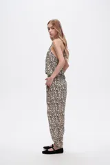 Pantalón slouchy de viscosa con estampado floral en tonos beige y negro, bolsillos laterales, cintura alta y detalle de punto smock en los tobillos.