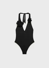 Traje de baño enterizo negro con escote halter y espalda descubierta. Presenta detalle de flor grande en el cuello.