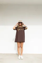 Remerón marrón con cuello y mangas con ribete amarillo, y estampado frontal con la palabra 'W.A.N.D.' en amarillo.