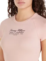 Remera rosa de algodón con cuello redondo y mangas cortas raglán. Estampado frontal con el logo de Tommy Hilfiger en negro.