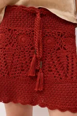 Minifalda tejida a crochet color ladrillo, con cintura alta y cordón trenzado con borlas.