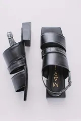 Sandalias bajas color crema con tres tiras en la capellada, una de ellas con textura tipo piel de cocodrilo. Pulsera con hebilla para ajustar al tobillo y taco cuadrado color negro.