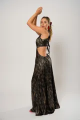 Vestido largo de fiesta con estampado abstracto en tonos dorados y negros. Tiene escote en V, corte en la cintura y aberturas laterales.