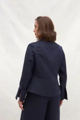 Chaqueta color crema de lino, de corte recto, con cuello camisero y cierre frontal con botones.