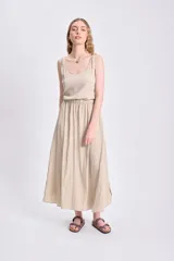 Vestido midi color beige, sin mangas, con corte a la cintura con elástico.