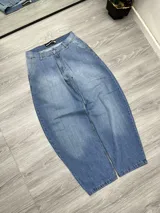 Pantalón de jean celeste con corte holgado, bolsillos cuadrados y bordado de cruz en el bolsillo trasero.