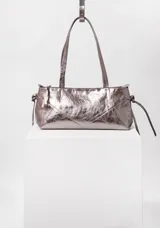 Cartera tipo baguette color lila metalizado con cierre metálico color níquel y bolsillo interno con cierre. Interior 100% algodón.