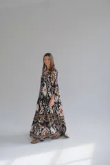 Vestido largo con estampado abstracto en tonos negro, blanco y marrón. Tiene escote en V, mangas 3/4 y corte escalonado.