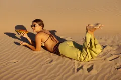 Pantalón de lino color amarillo, de corte ancho y tiro medio. Presenta detalles de estampa con motivos geométricos en la cintura y laterales.