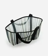Bolso de playa rectangular de poliéster con rayas verticales en tonos de verde, gris y blanco. Tiene asas de algodón negras y un bolsillo externo.