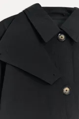 Trench confeccionado con hilatura de algodón color negro, con cuello solapa, manga larga acabada en puño, solapa con trabilla y botón en cuello, bolsillos laterales, cinturón lazada en mismo tejido, bajo con abertura en espalda y cierre frontal con botones.