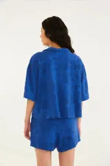 Camisa azul de toalla con cuello clásico, corte suelto, mangas cortas amplias y cierre con lazo.