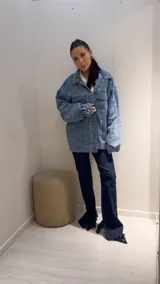 Campera de jean celeste con tachas plateadas, corte oversized, cuello clásico, cierre con botones metálicos y bolsillos delanteros.