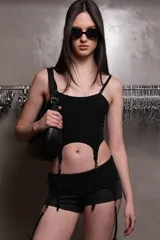 Corset negro de microfibra liviana embutido con escote recto, recortes y ballenas insertadas en cinta bies. Breteles desmontables con avíos metálicos regulables y embutidos en base. Detalle de avío pasador de marca en terminación inferior con tira elástica y portaligas metálico. Espalda con panal realizado en hilo elástico como ajuste.