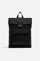 Mochila negra de tejido técnico con solapa y hebilla. Tiene un bolsillo frontal, un bolsillo interior con cierre y un compartimento para dispositivos electrónicos de hasta 13 pulgadas. La parte posterior es acolchada y tiene una banda de sujeción para equipaje.