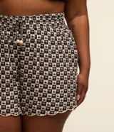 Salida de playa plus size modelo short, confeccionada en viscosa más sostenible, con cintura elástica, bajo con acabado ondulado, superficie de cuadros con estampa de cocoteros y lazo en la cintura.